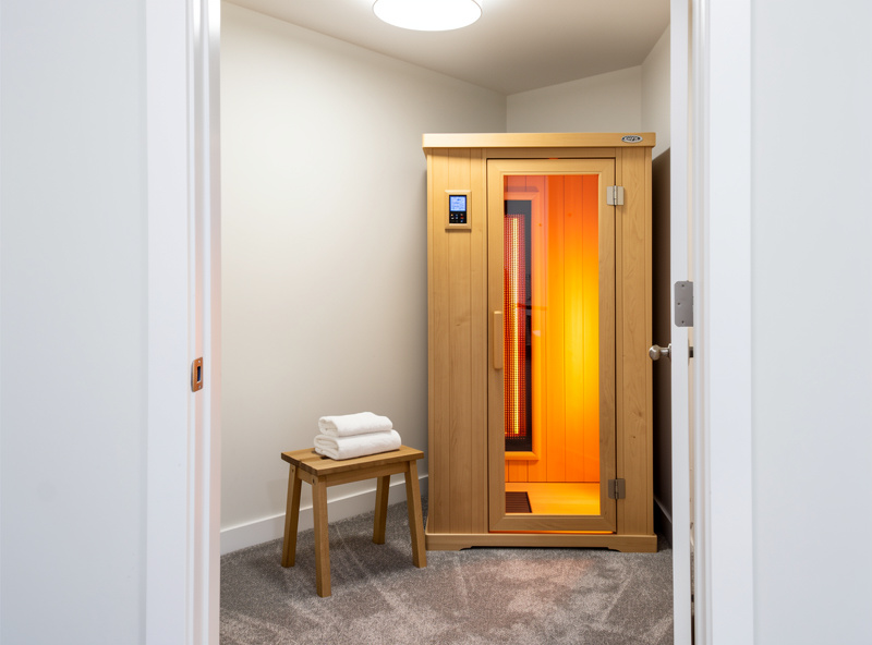 Compact one-person infrared sauna installed in a converted apartment walk-in closet next to folded towels