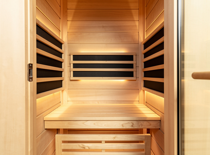 Interior of far-infrared sauna cabin with carbon panel heaters and warm wood interior, no LED lights
