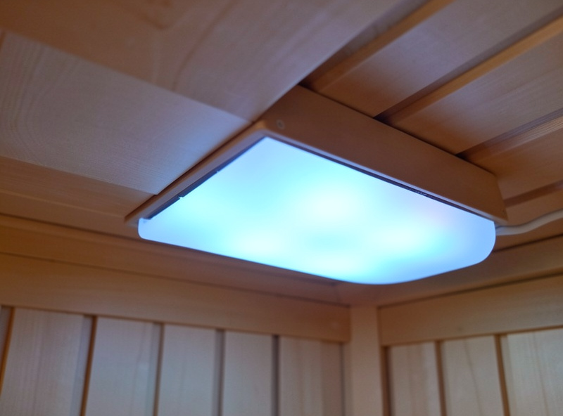 RGB chromotherapy LED light bar with frosted diffuser mounted on a sauna ceiling edge glowing soft blue