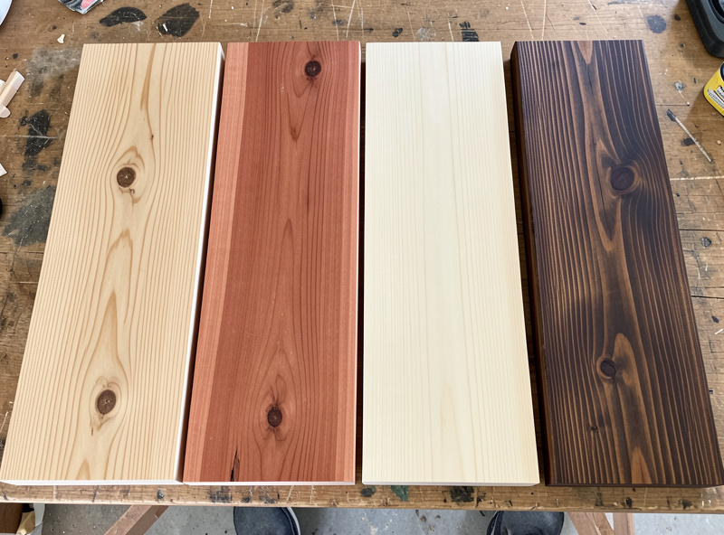 Sample boards of cedar, hemlock, basswood and thermally modified pine laid side by side on a workbench