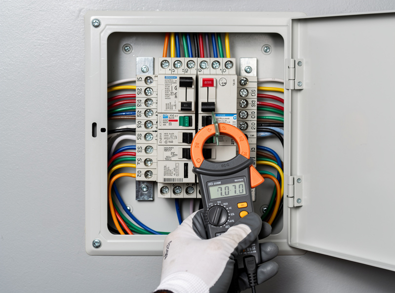 Residential breaker panel with a labeled dedicated double-pole breaker and a clamp meter