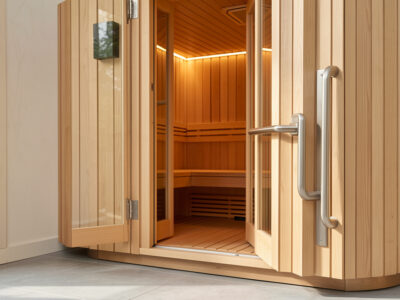 Infrared sauna entrance with a low flat threshold, open door, and brushed steel grab bar in warm light