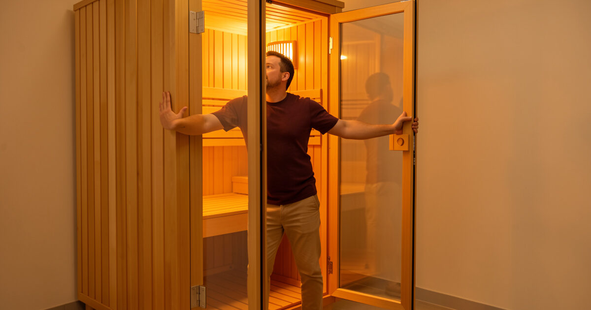 Person opening an infrared sauna door wide to air out the cabin