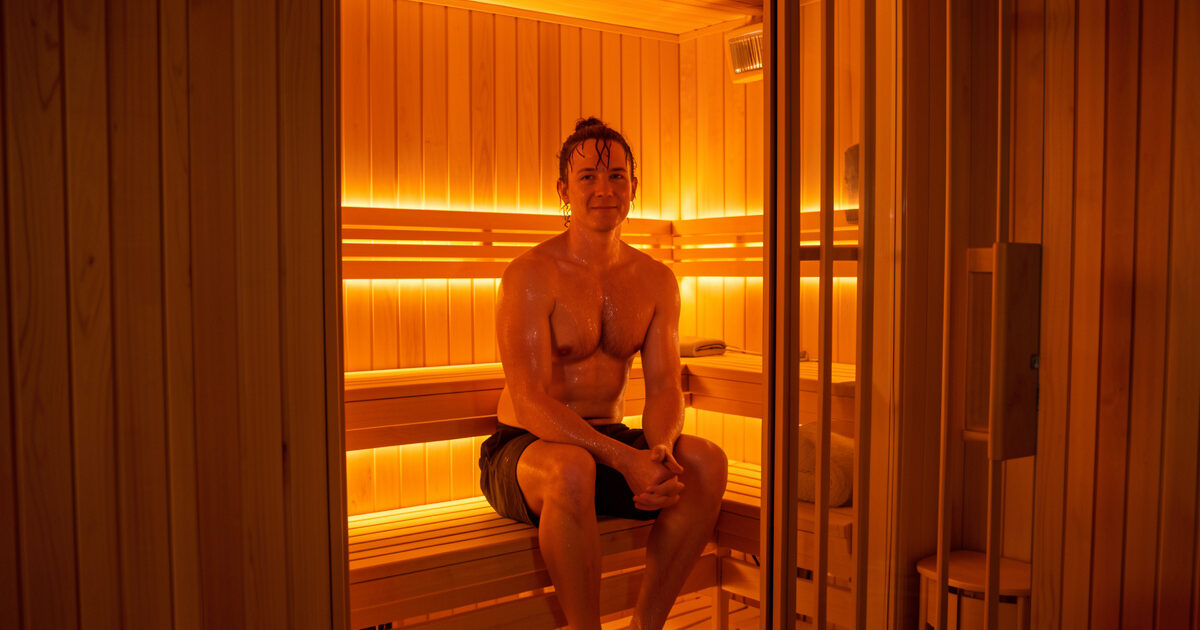 Person sweating during a session in a glowing infrared sauna cabin
