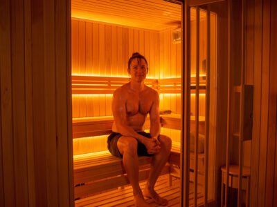 Person sweating during a session in a glowing infrared sauna cabin