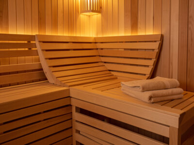 Infrared sauna bench with an ergonomic slanted basswood backrest, folded towel, and warm light