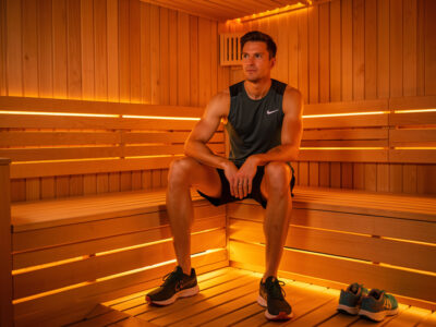Distance runner sitting on an infrared sauna bench after a run with shoes to the side