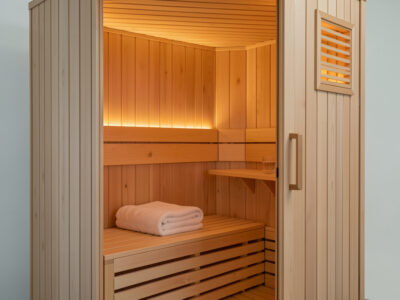 Gentle low-temperature infrared sauna cabin with a folded towel and a glass of water on the bench