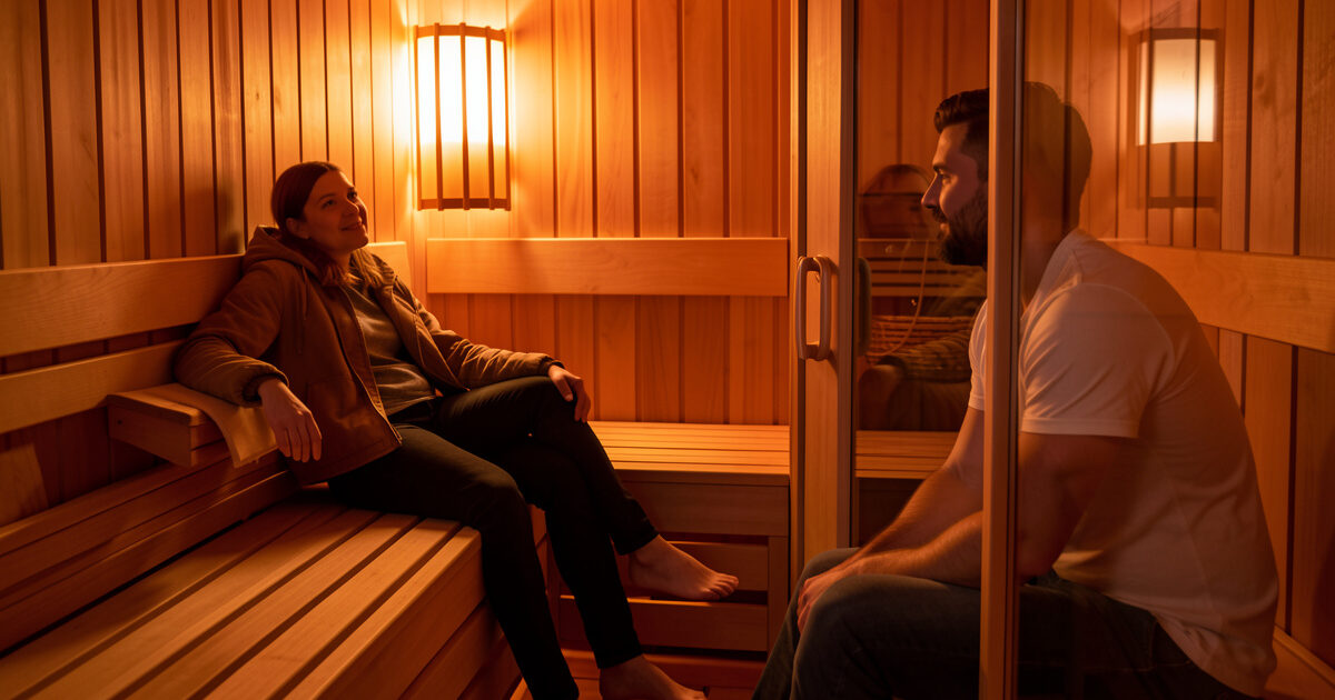 Two people in an infrared sauna sitting at different distances from the heater panel