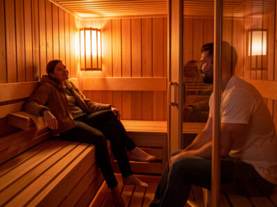 Two people in an infrared sauna sitting at different distances from the heater panel