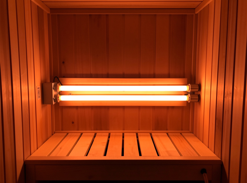 Full-spectrum infrared sauna interior with a bright near-infrared halogen emitter tube glowing at the front