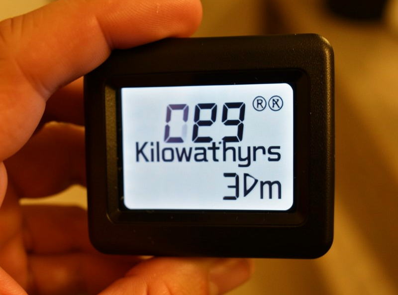 Close-up of a plug-in energy monitor display showing a kilowatt-hours reading