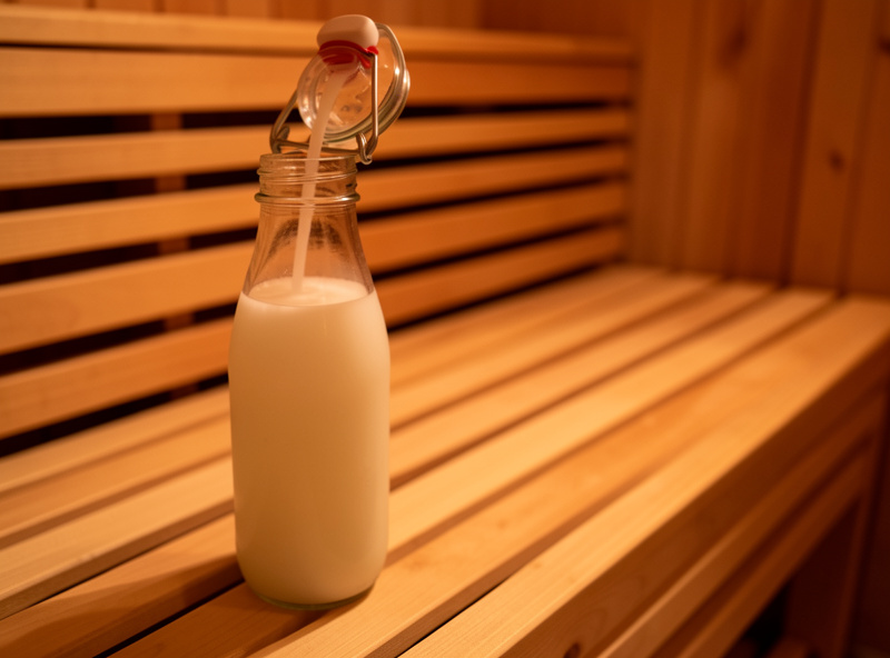 Electrolyte drink being poured into an insulated bottle beside a sauna bench