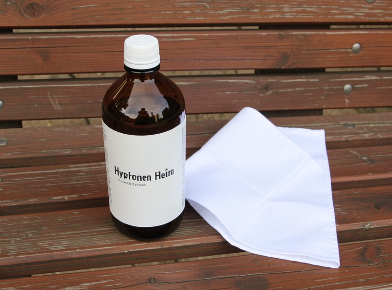 A brown bottle of three percent hydrogen peroxide beside a white cloth on a wooden bench